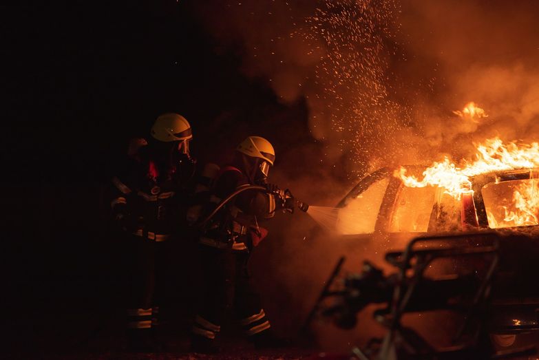 Strażacy gaszący pożar samochodu